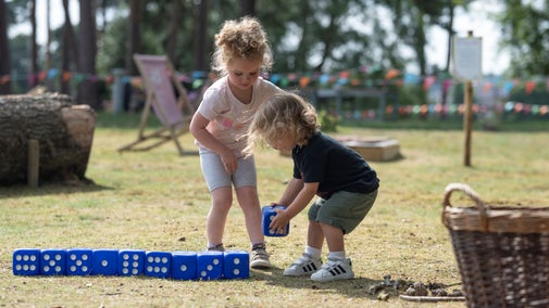 A young boy and girl playing with large dice in the sunshine